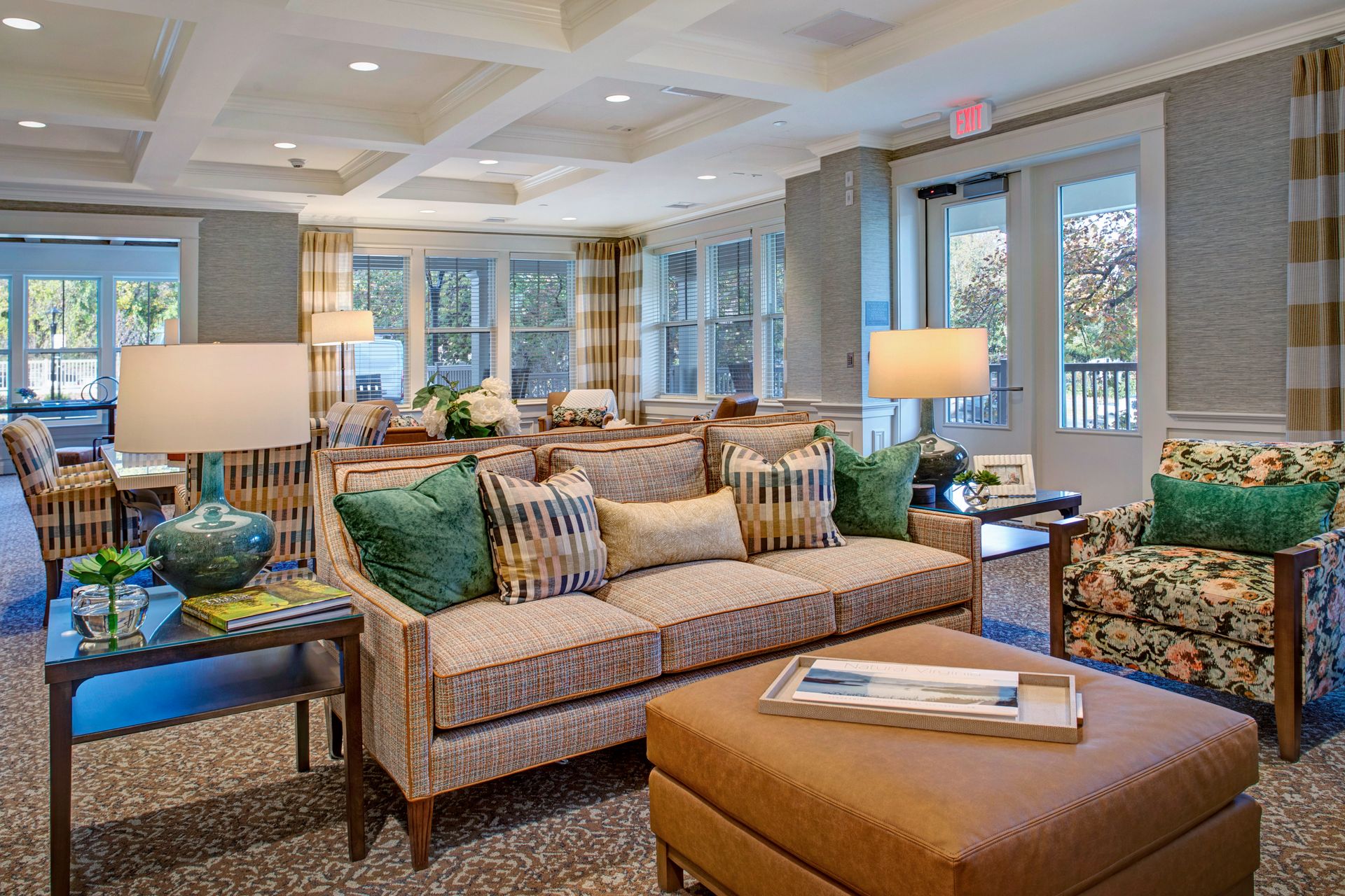 A living room with a couch , chairs , ottoman and lamps.