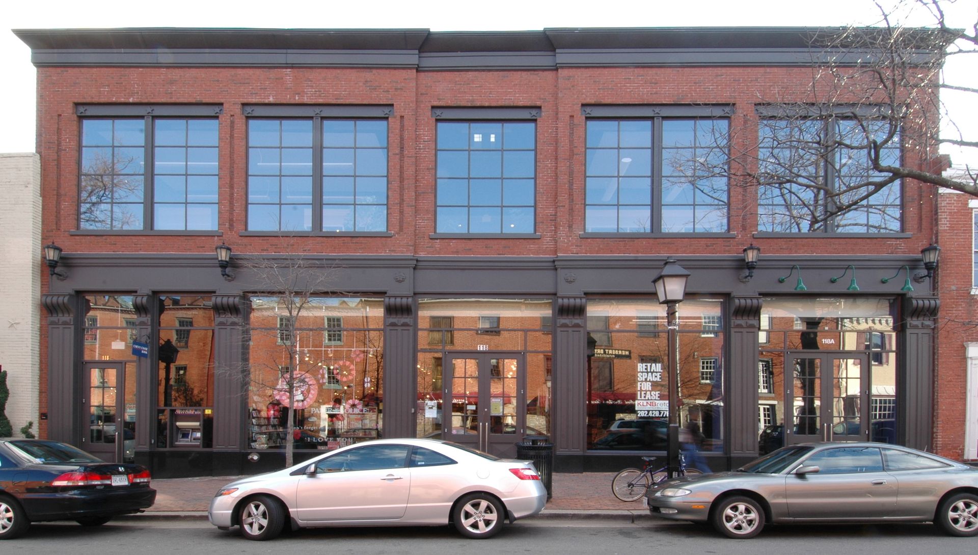 A row of cars are parked in front of a large brick building