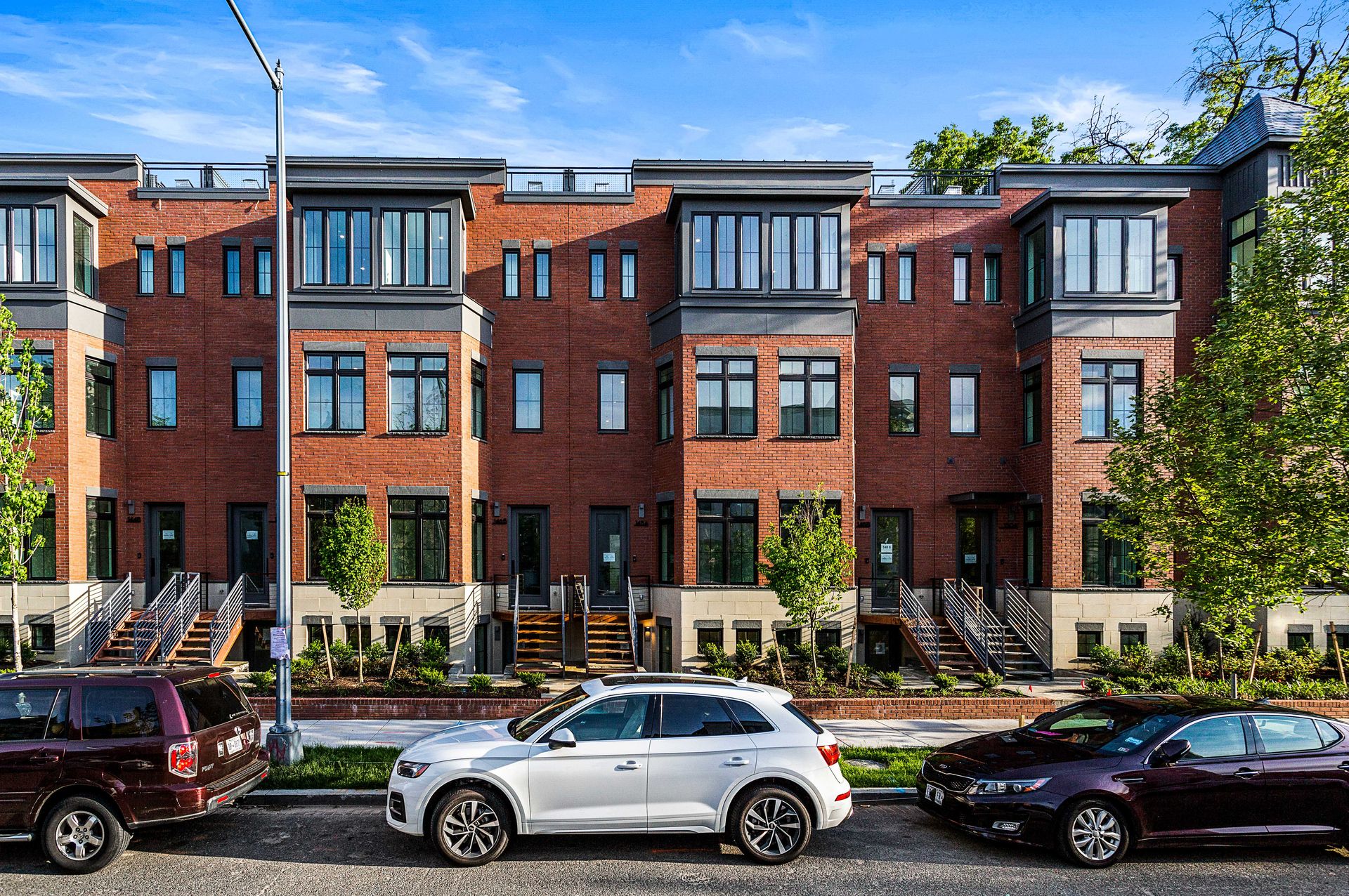 A row of brick buildings with cars parked in front of them.