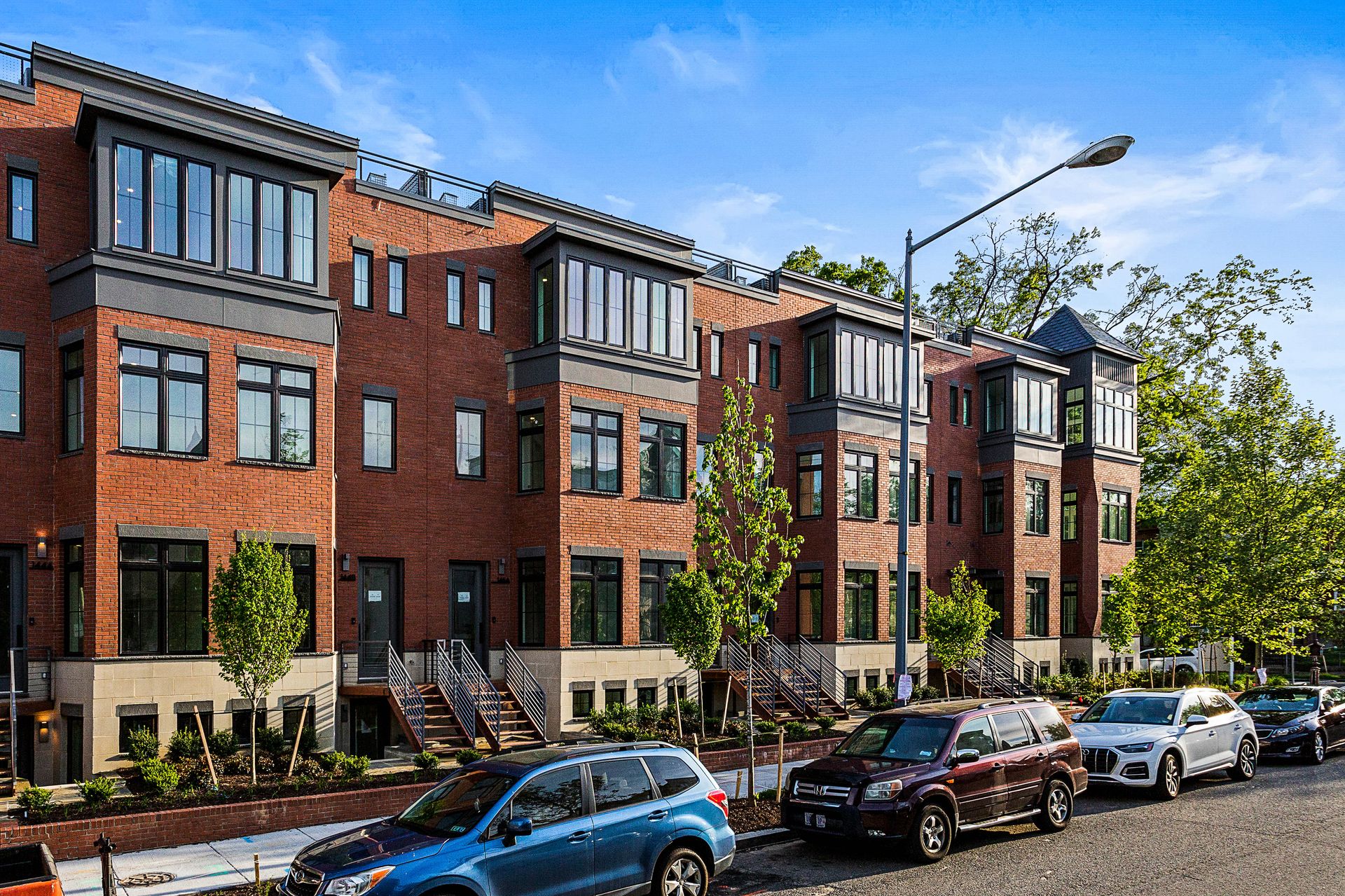 A row of brick buildings with cars parked in front of them.