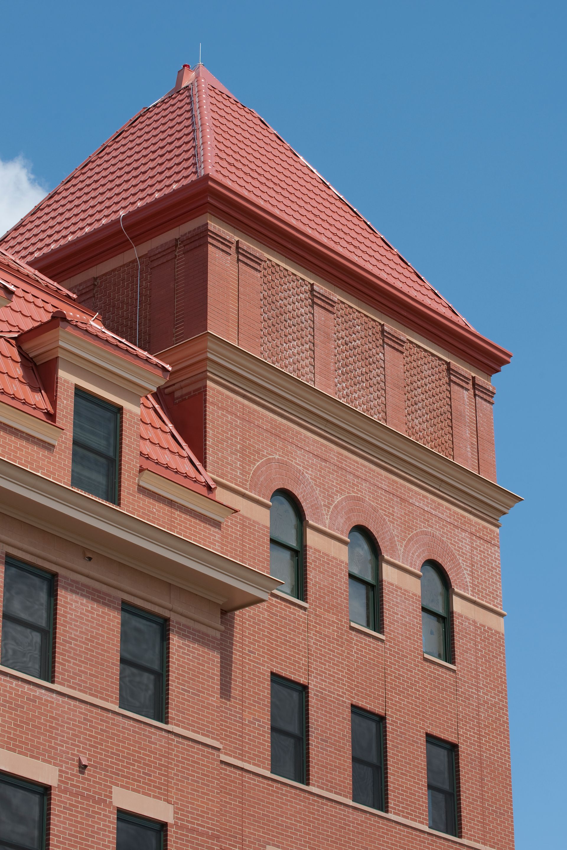 A brick building with arched windows and a red roof
