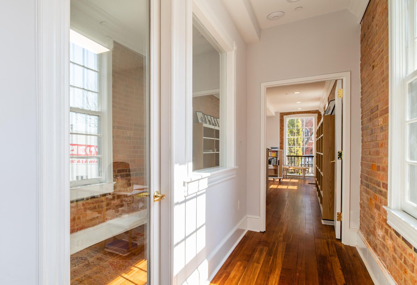 A hallway with hardwood floors and a brick wall