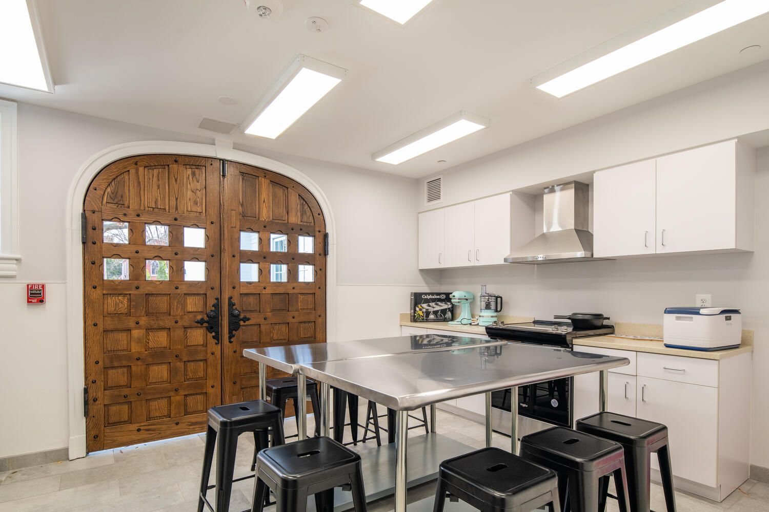 A kitchen with a table and stools and a wooden door.