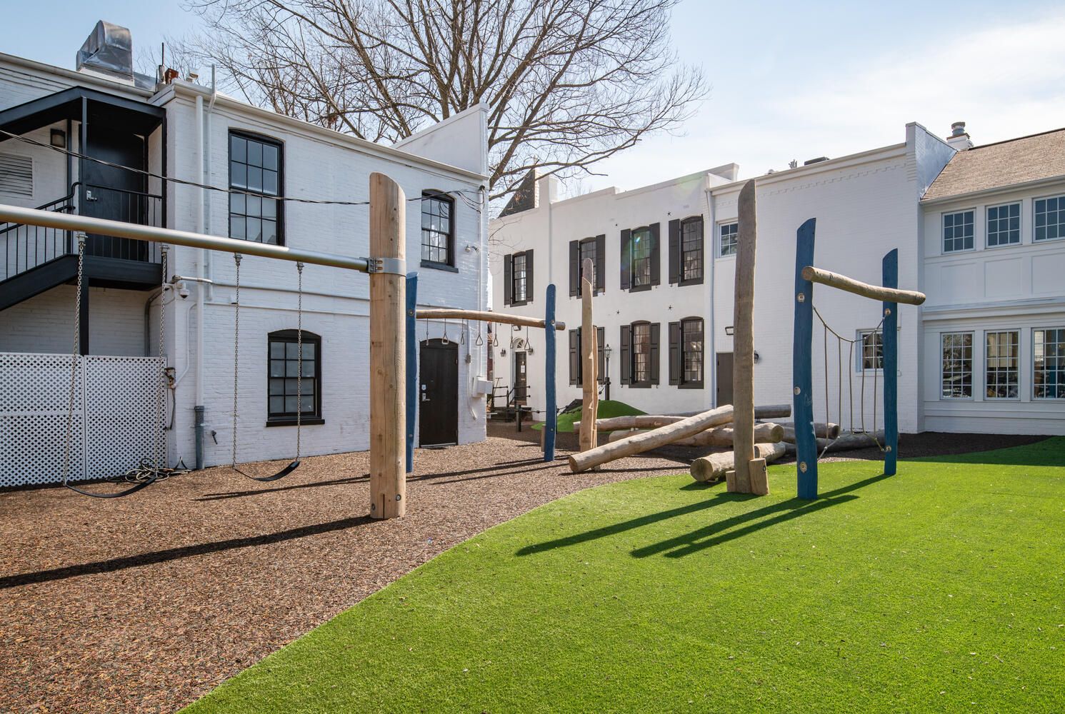 A white building with a playground in front of it.