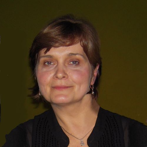 A woman wearing a black shirt and earrings is smiling for the camera.