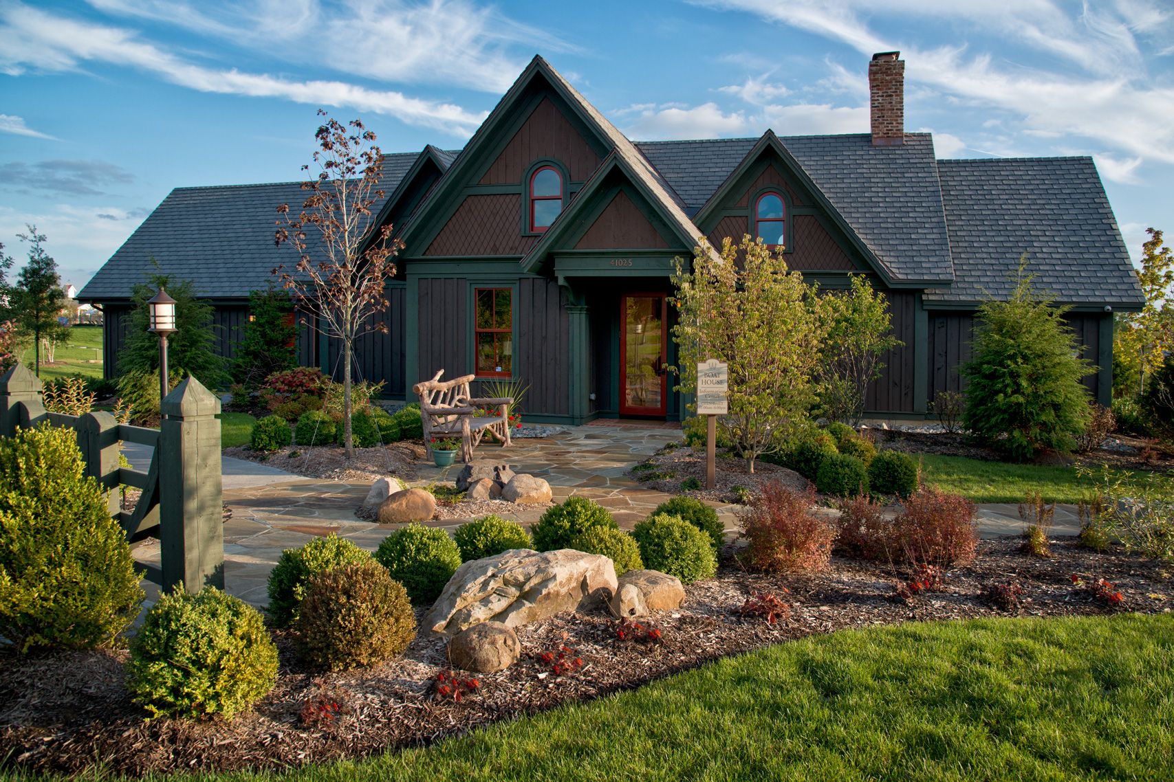 A large house with a slate roof sits in the middle of a lush green field.