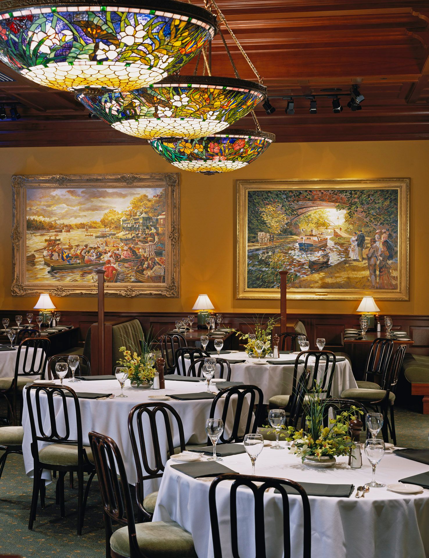 A dining room with tables and chairs and paintings on the wall