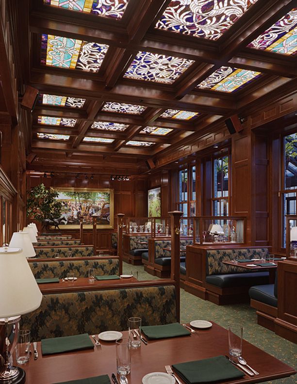 A dining room with tables and stained glass ceilings
