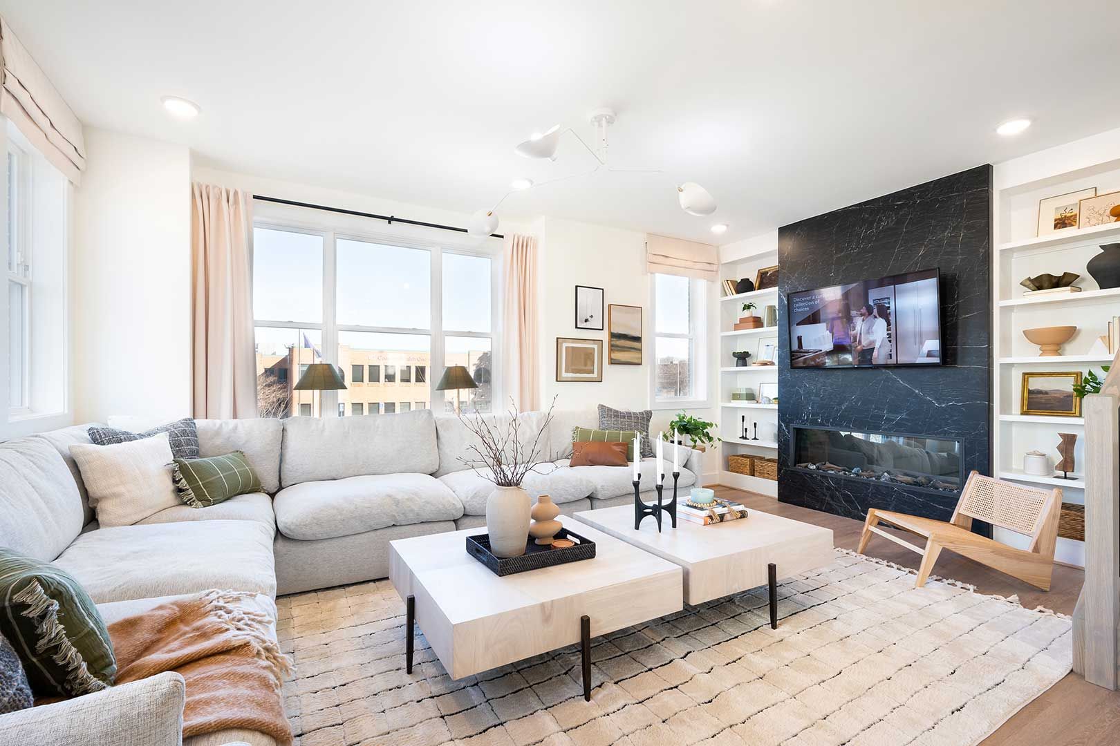 A living room with a couch , two coffee tables , a fireplace and a flat screen tv.