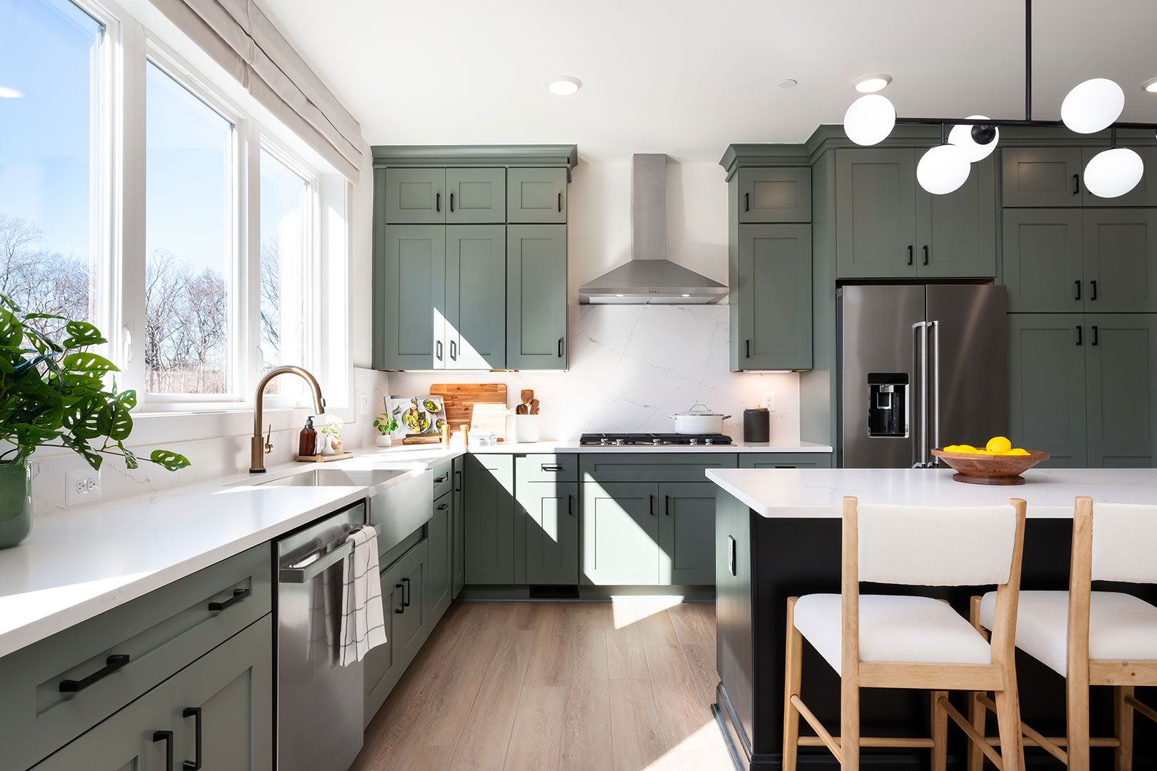 A kitchen with green cabinets and stainless steel appliances