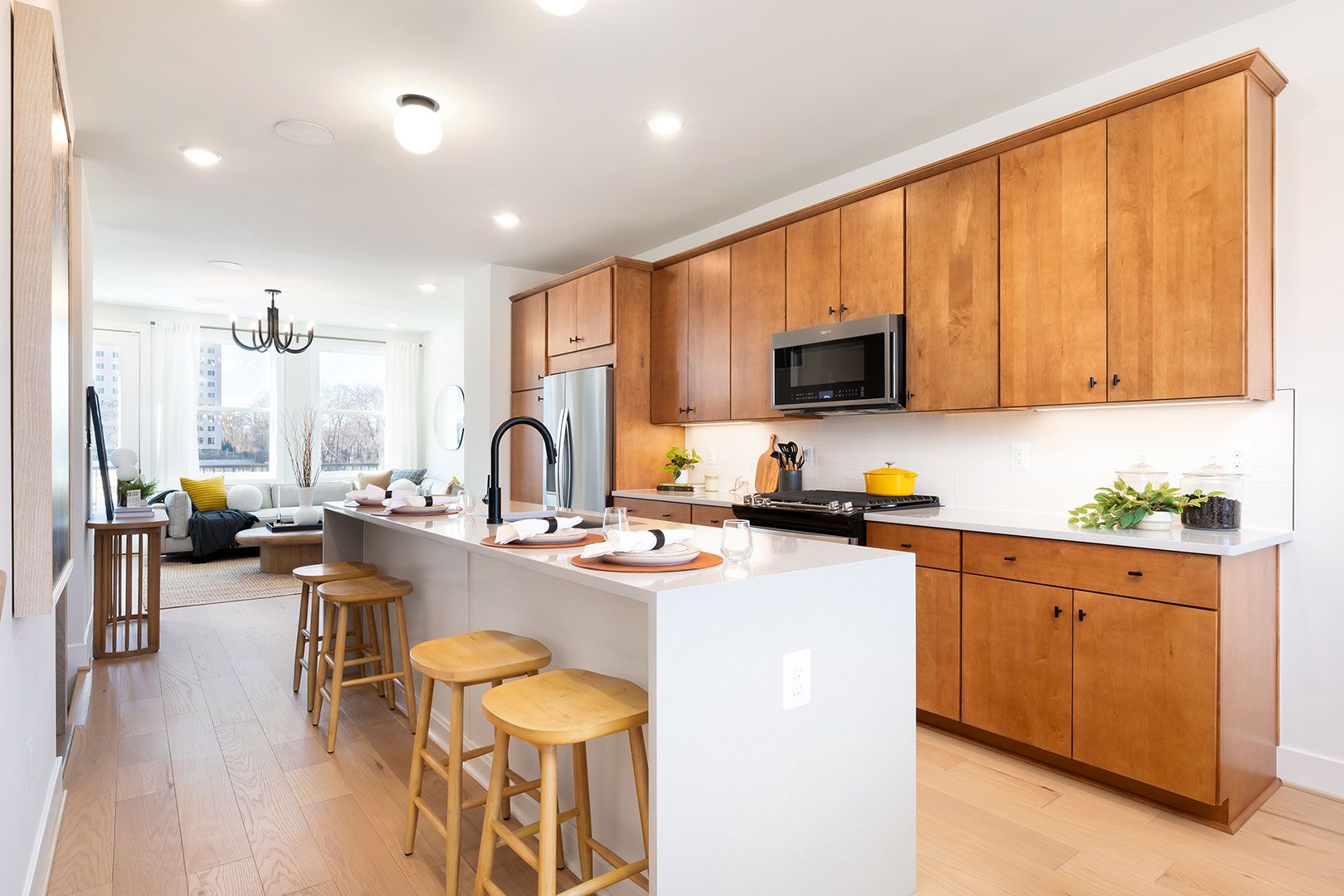 A kitchen with wooden cabinets and stools and a large island.