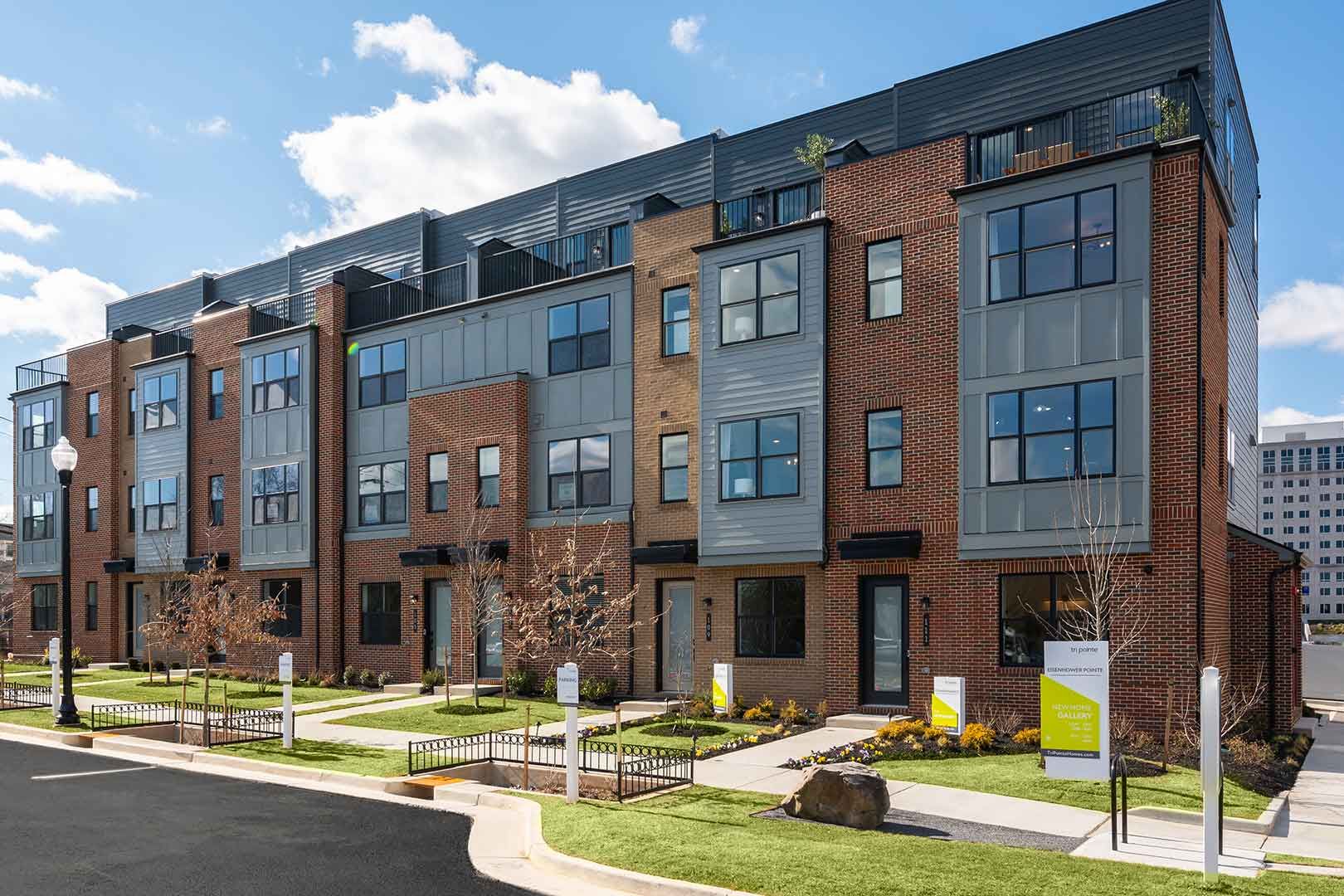 A large apartment building with a lot of windows and a lot of grass in front of it.