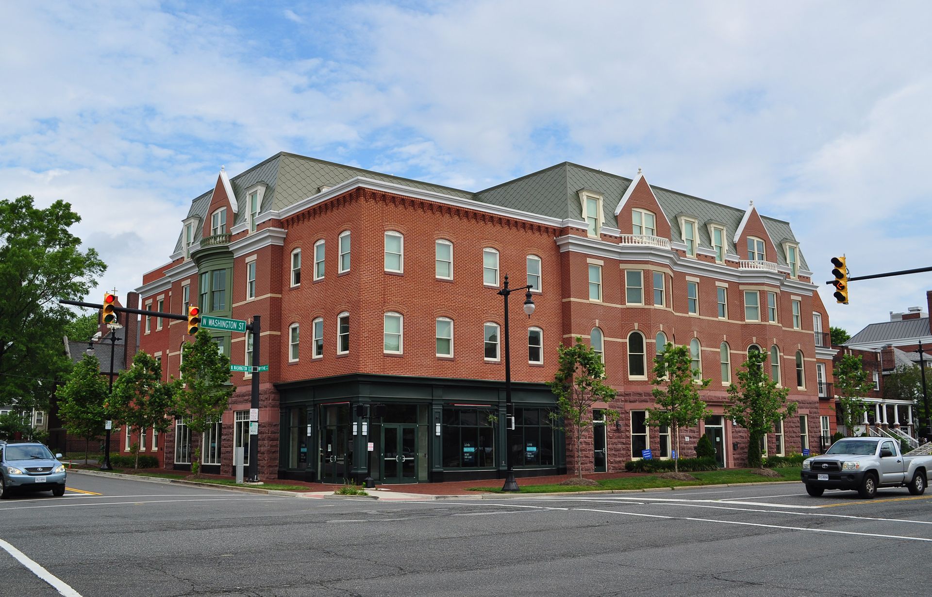 A large brick building is on the corner of a city street.
