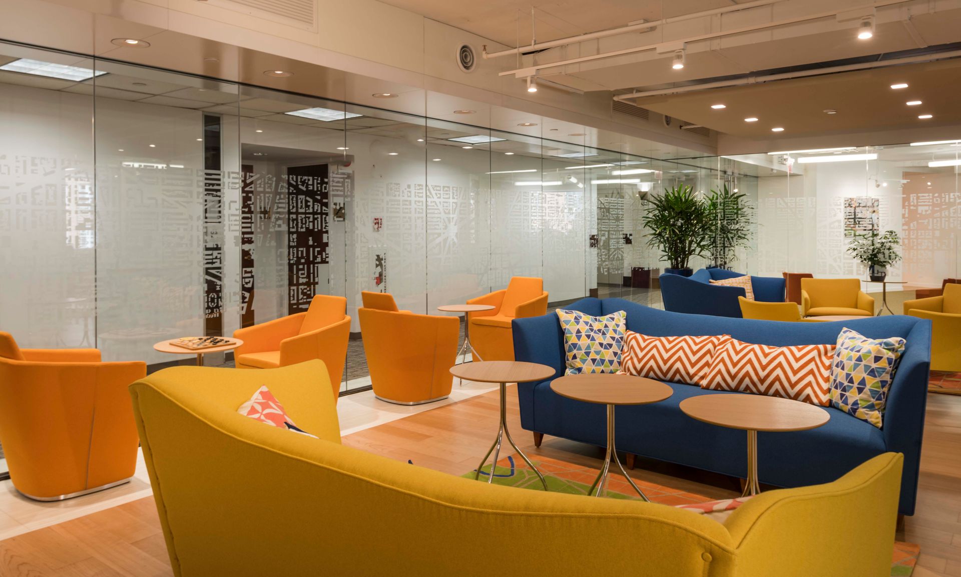 A living room with a blue couch , yellow chairs , and tables.