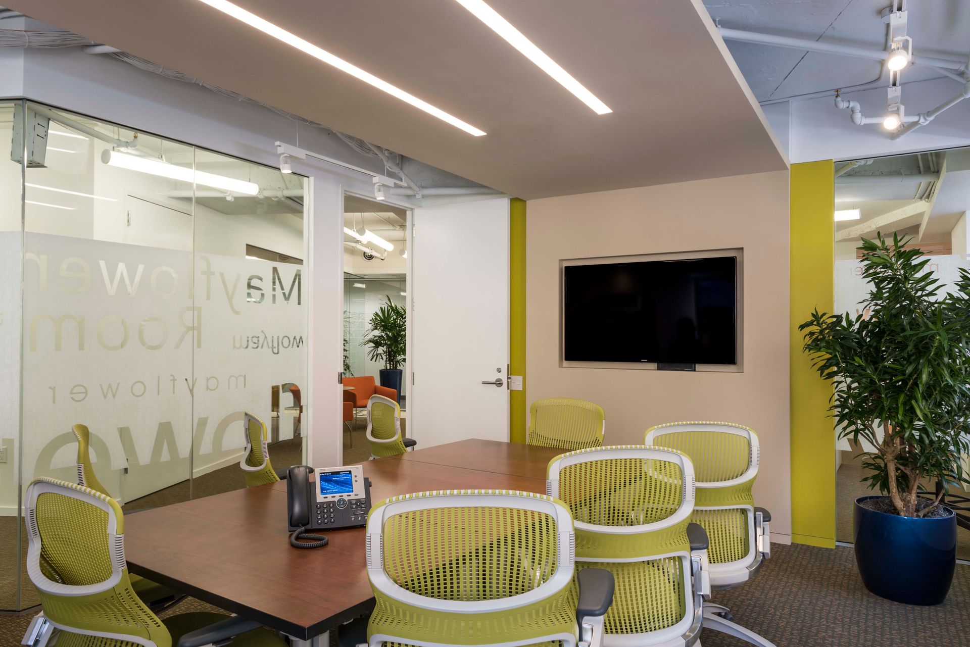 A conference room with a table and chairs and a flat screen tv.