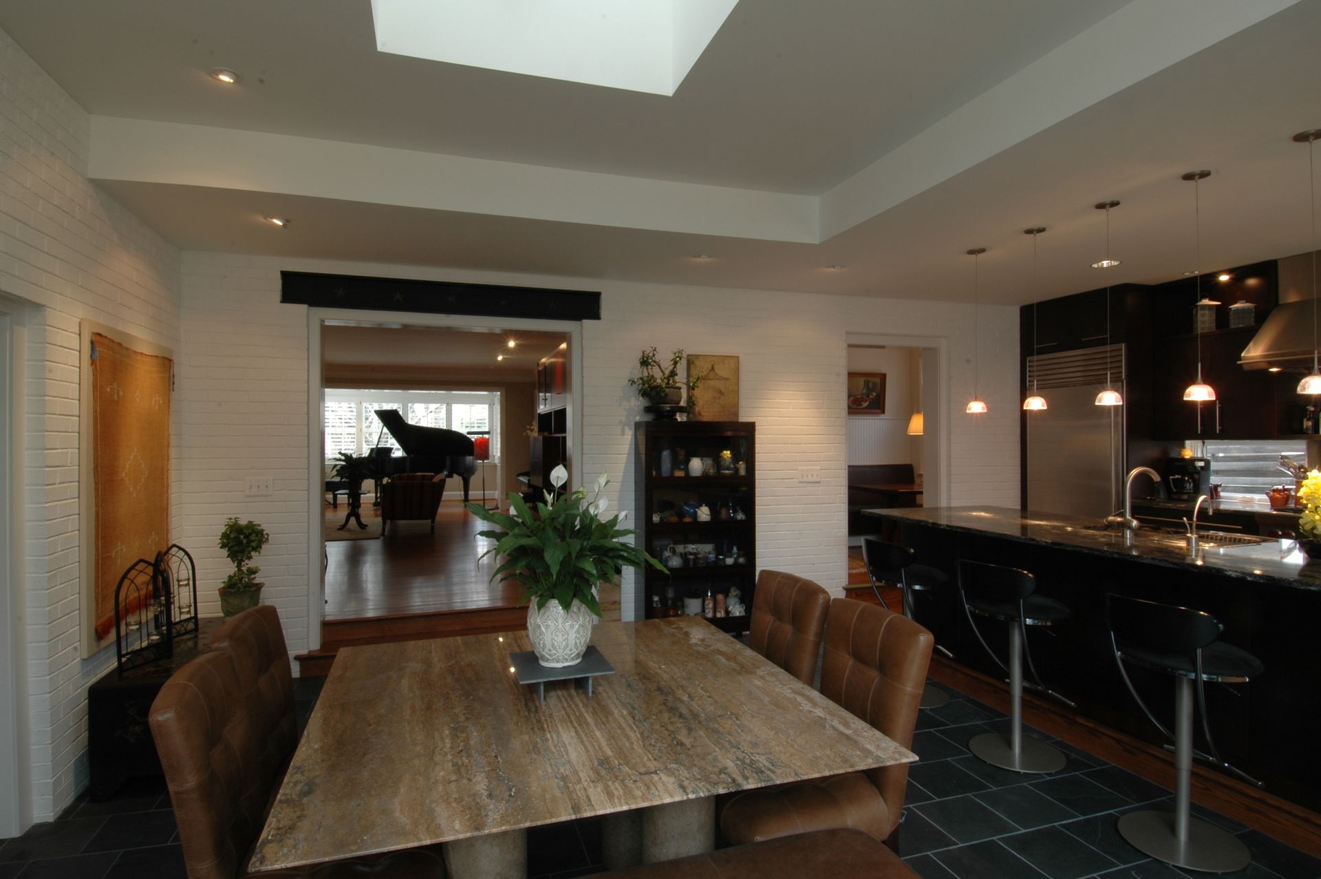 A dining room with a table and chairs and a piano in the background