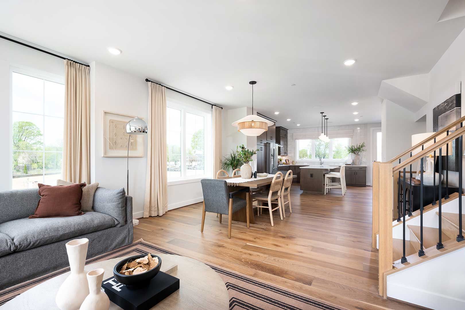 A living room with a couch , table , chairs and stairs.