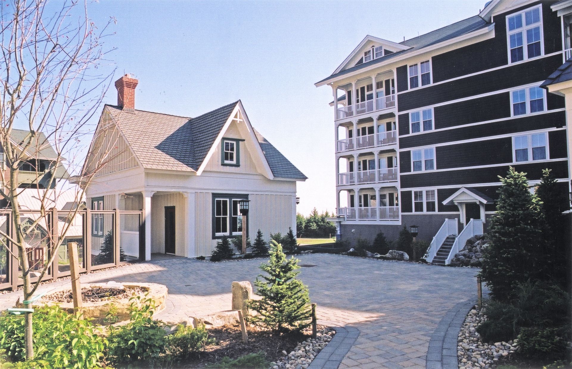 A small white house sits next to a large black building
