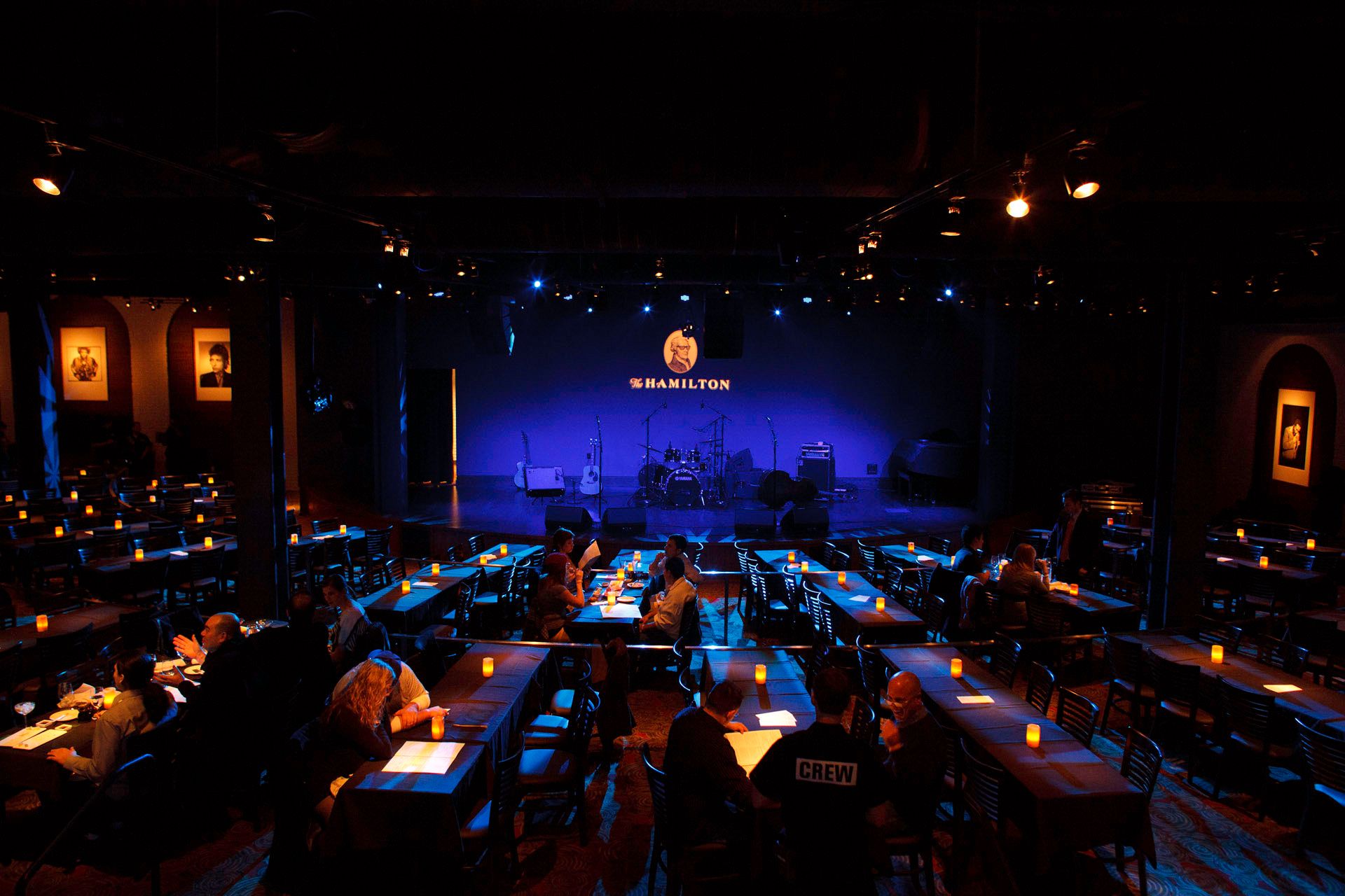 A group of people are sitting at tables in front of a stage that says ' the blue moon ' on it
