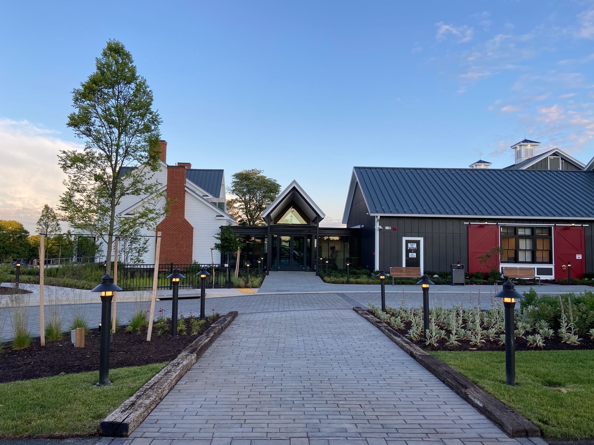 A brick walkway leading to a large building with a blue roof.