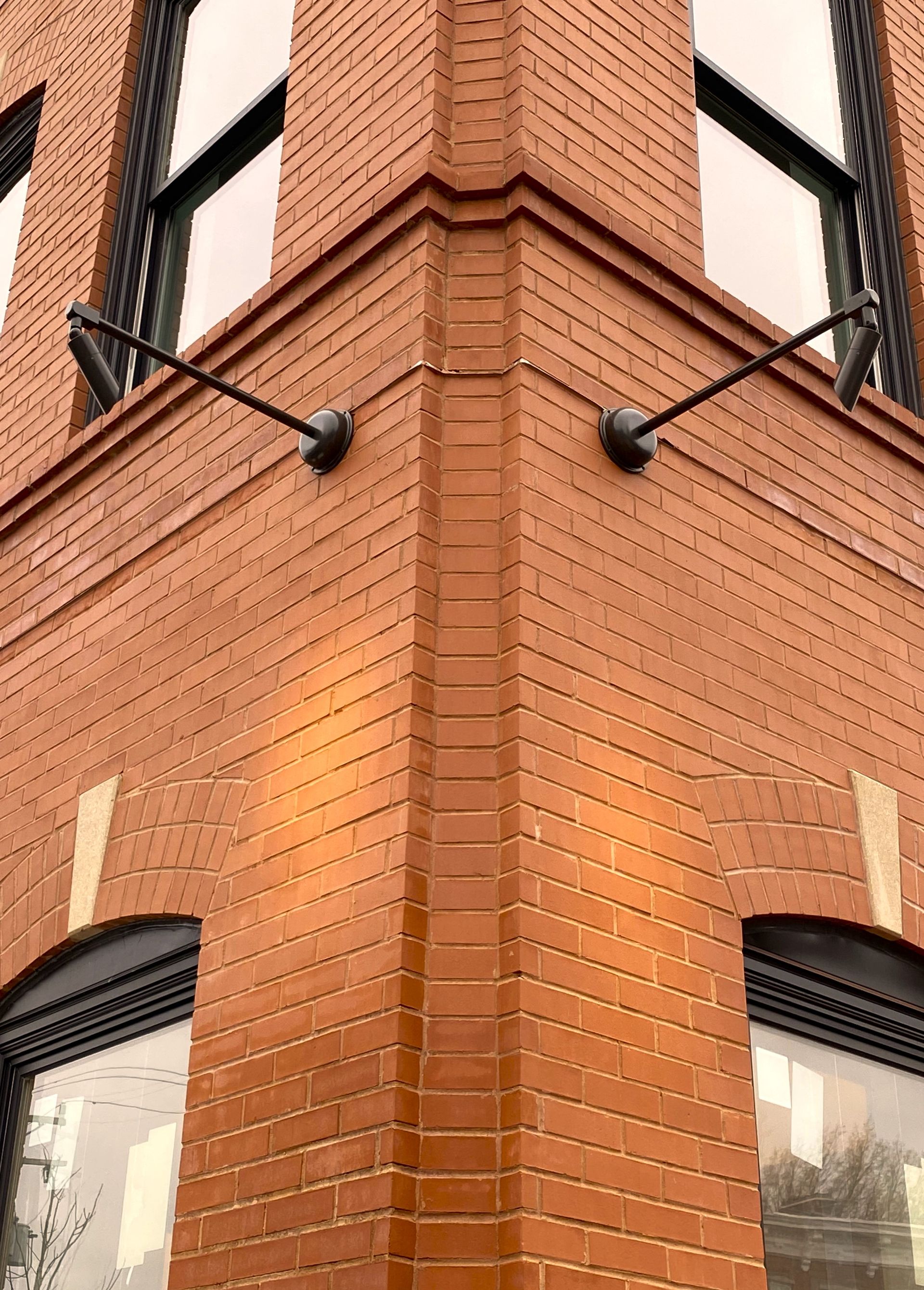 A close up of the corner of a brick building with a lot of windows.