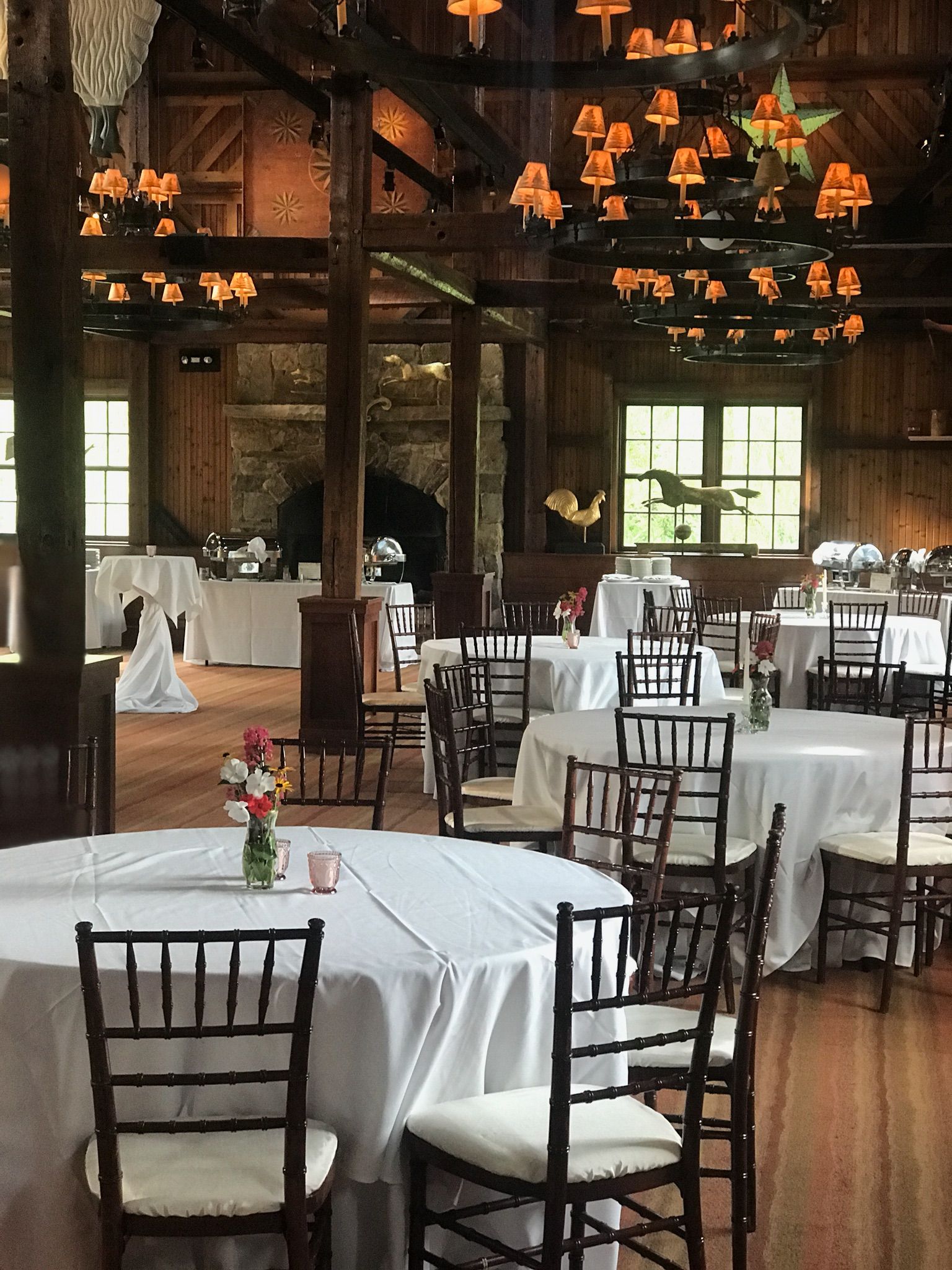 A large room with tables and chairs set up for a wedding reception