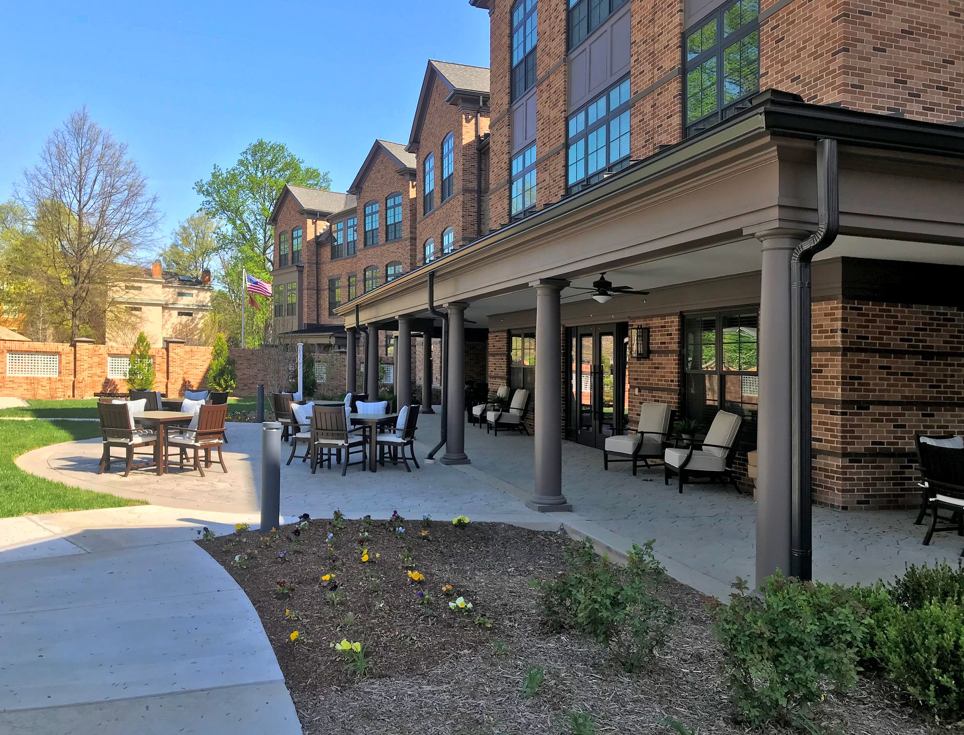 A large brick building with a patio area with tables and chairs.