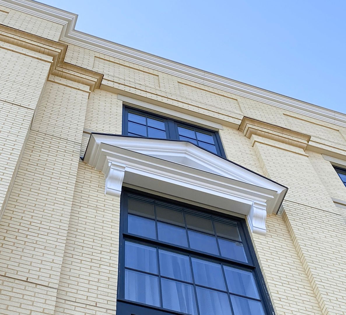 A yellow brick building with black windows and a blue sky in the background