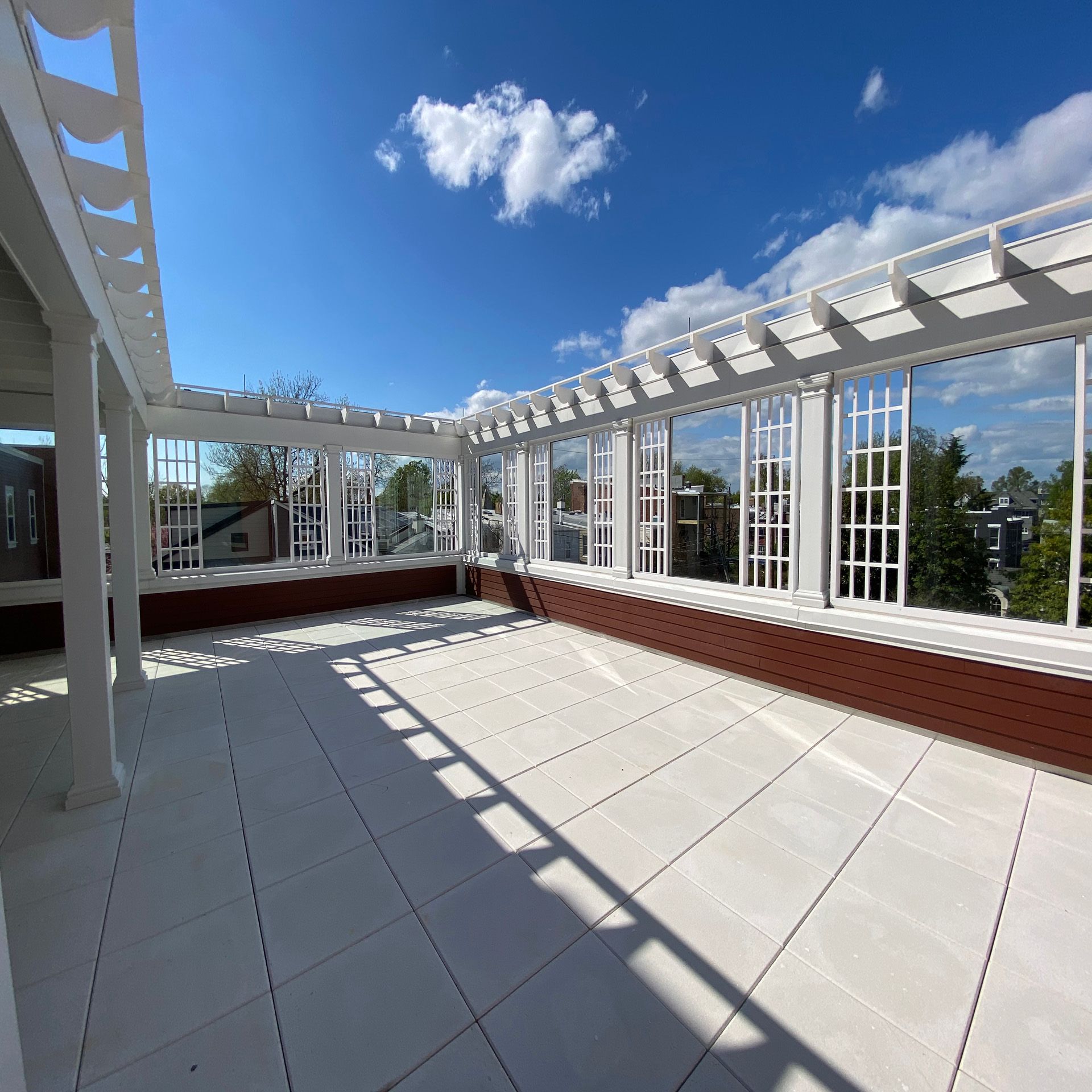 A rooftop deck with a pergola and lots of windows