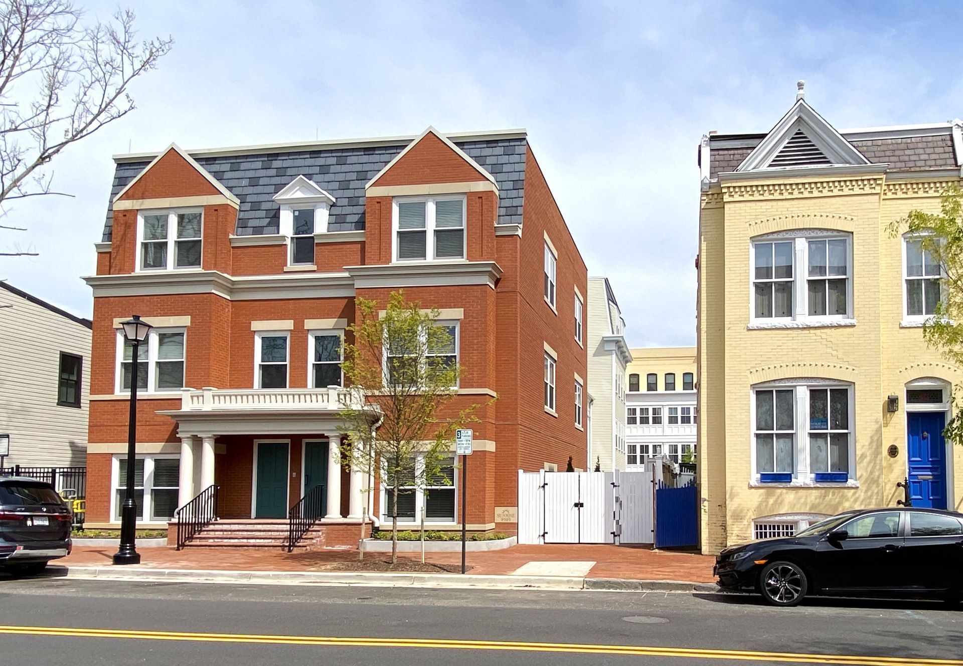 A black car is parked in front of a brick building