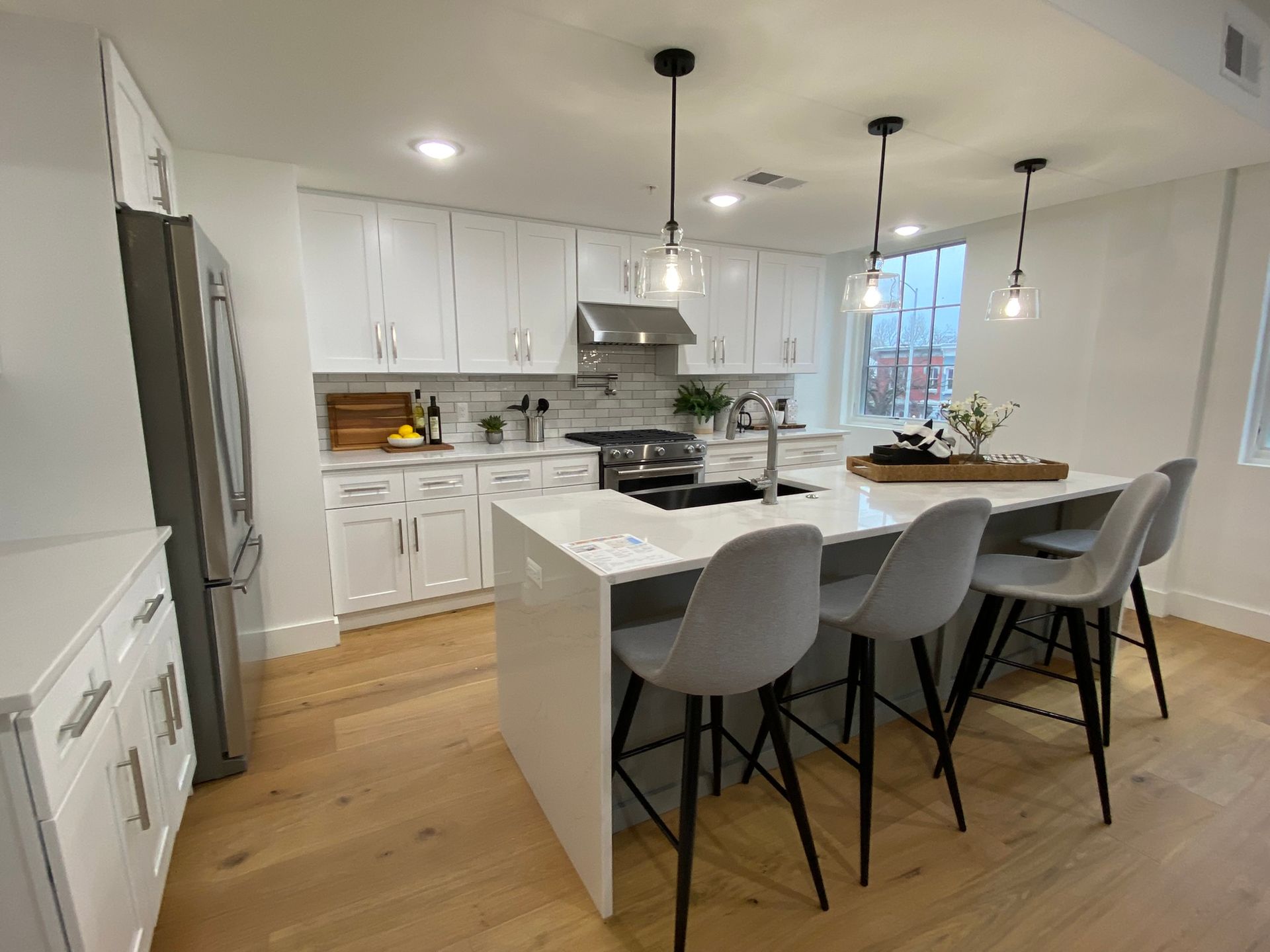 A kitchen with white cabinets , stainless steel appliances , and a large island.