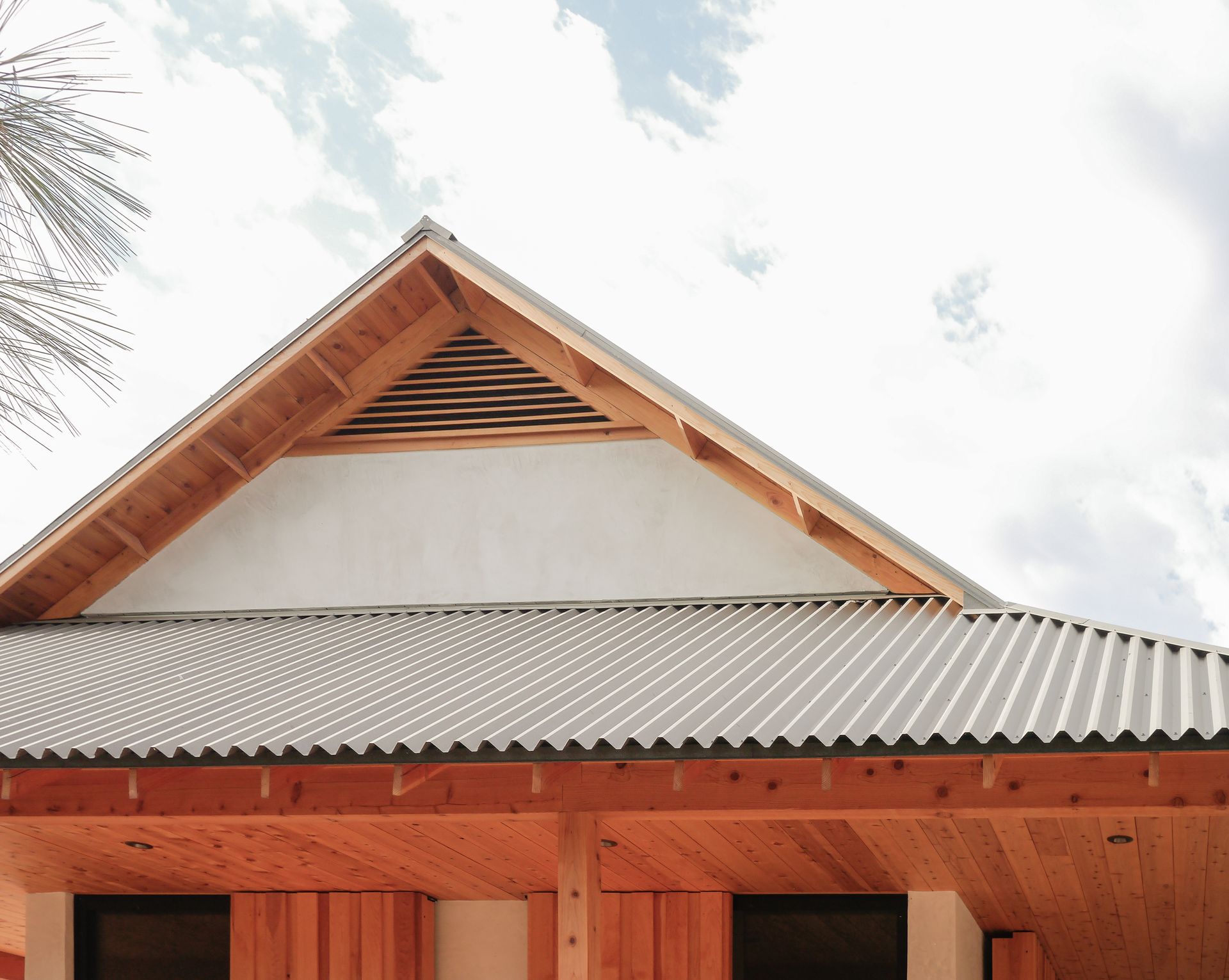 A wooden house with a metal roof and a palm tree in the background