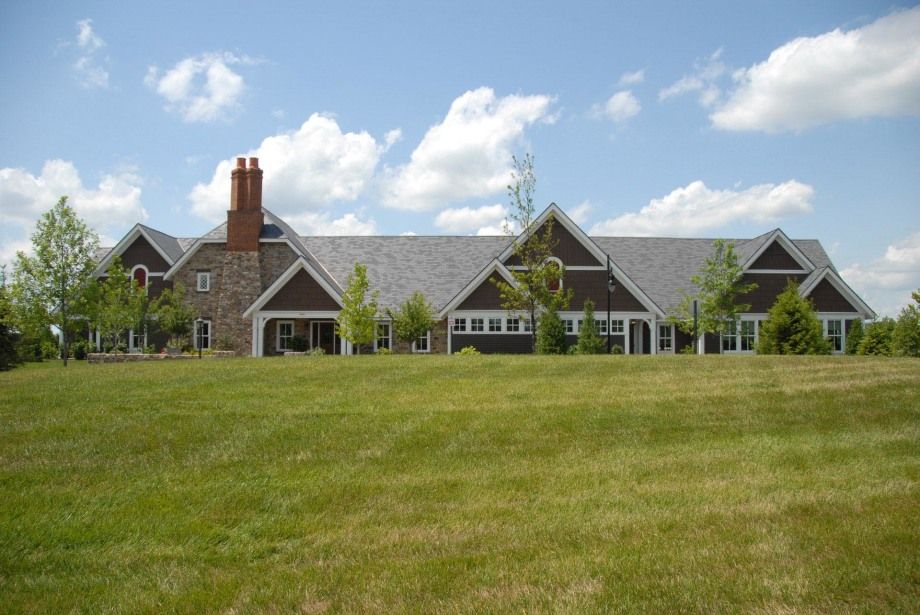 A large house sits in the middle of a lush green field