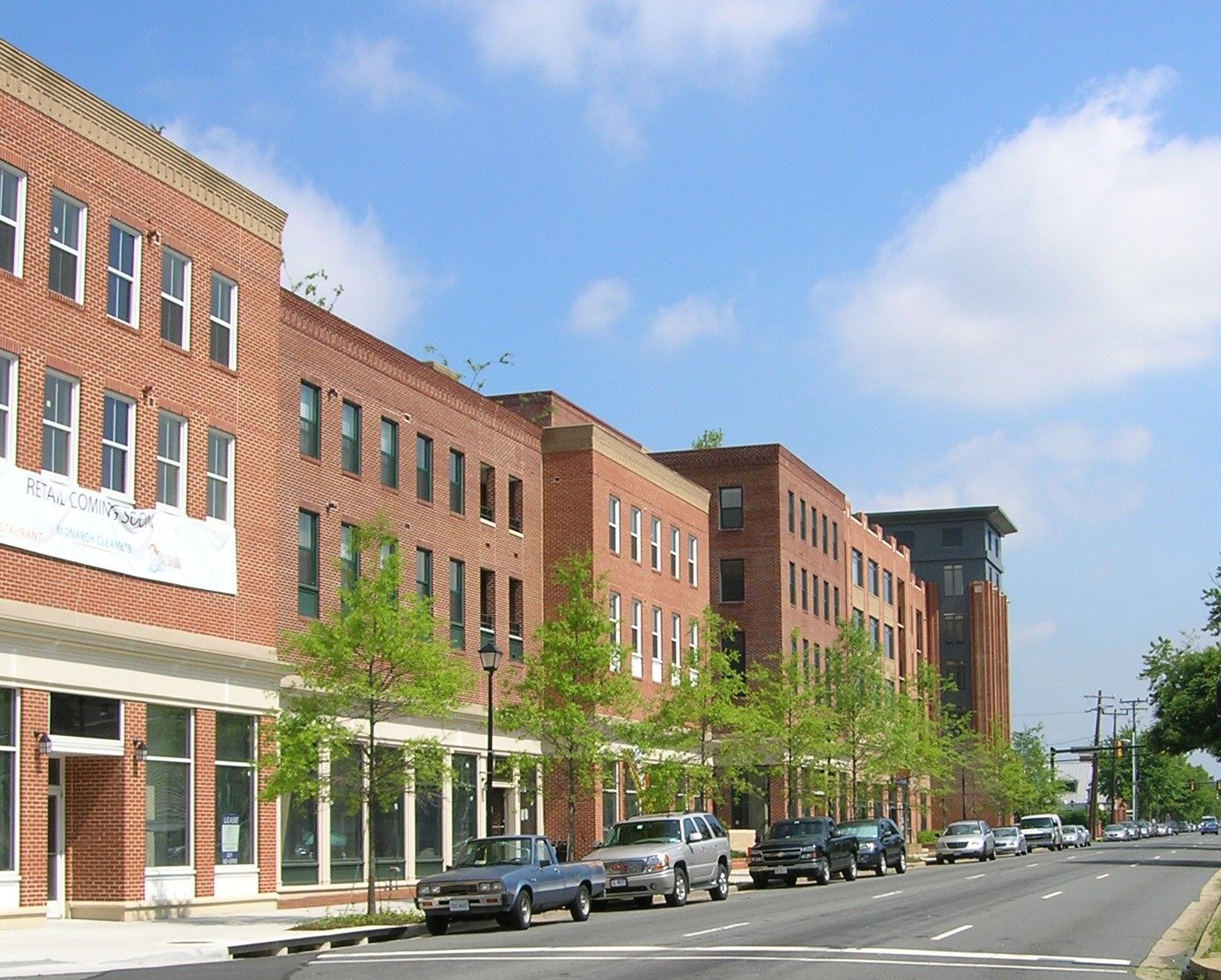 A row of brick buildings with cars parked in front of them