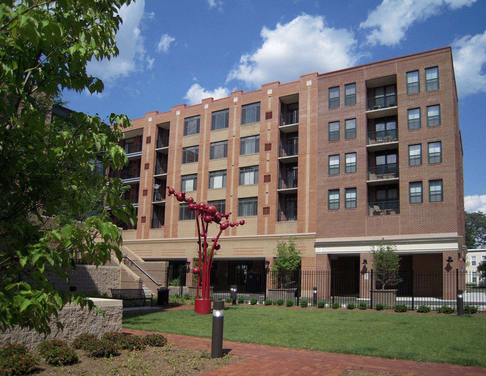 A large brick building with a red sculpture in front of it