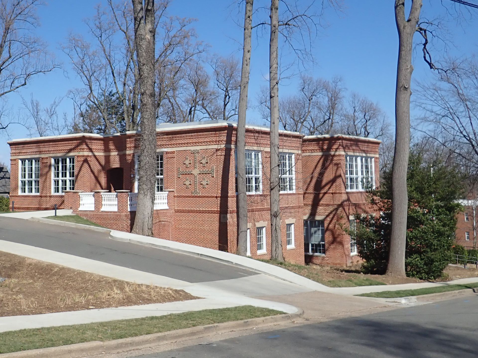 A brick building with trees in front of it on a sunny day