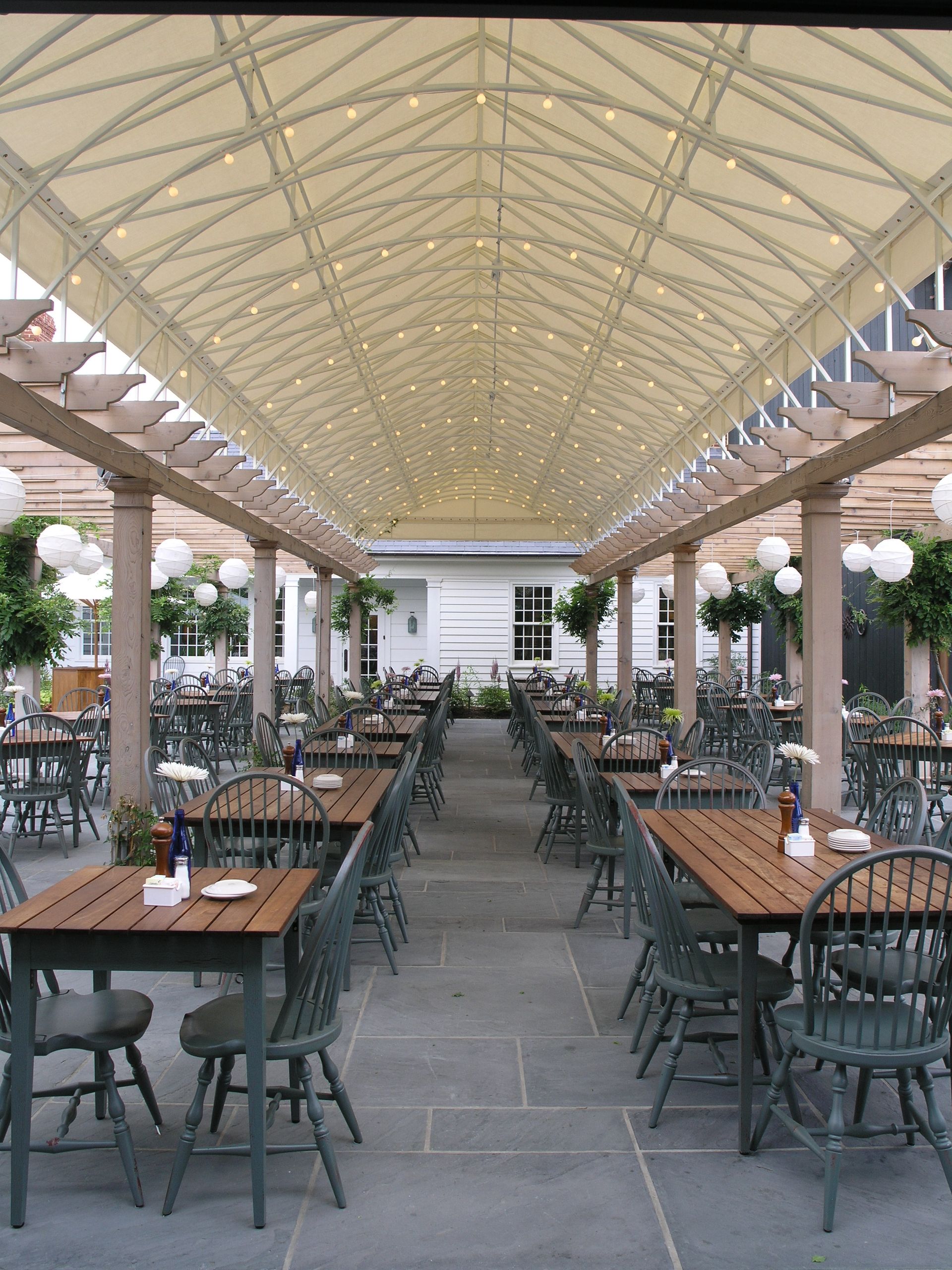 A restaurant with tables and chairs under a canopy