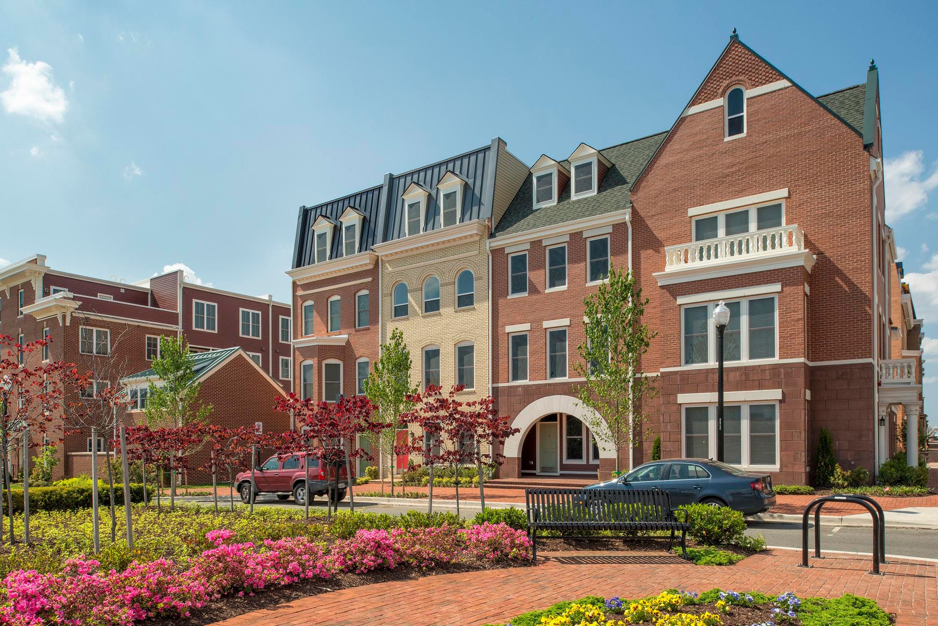 A row of brick buildings with cars parked in front of them