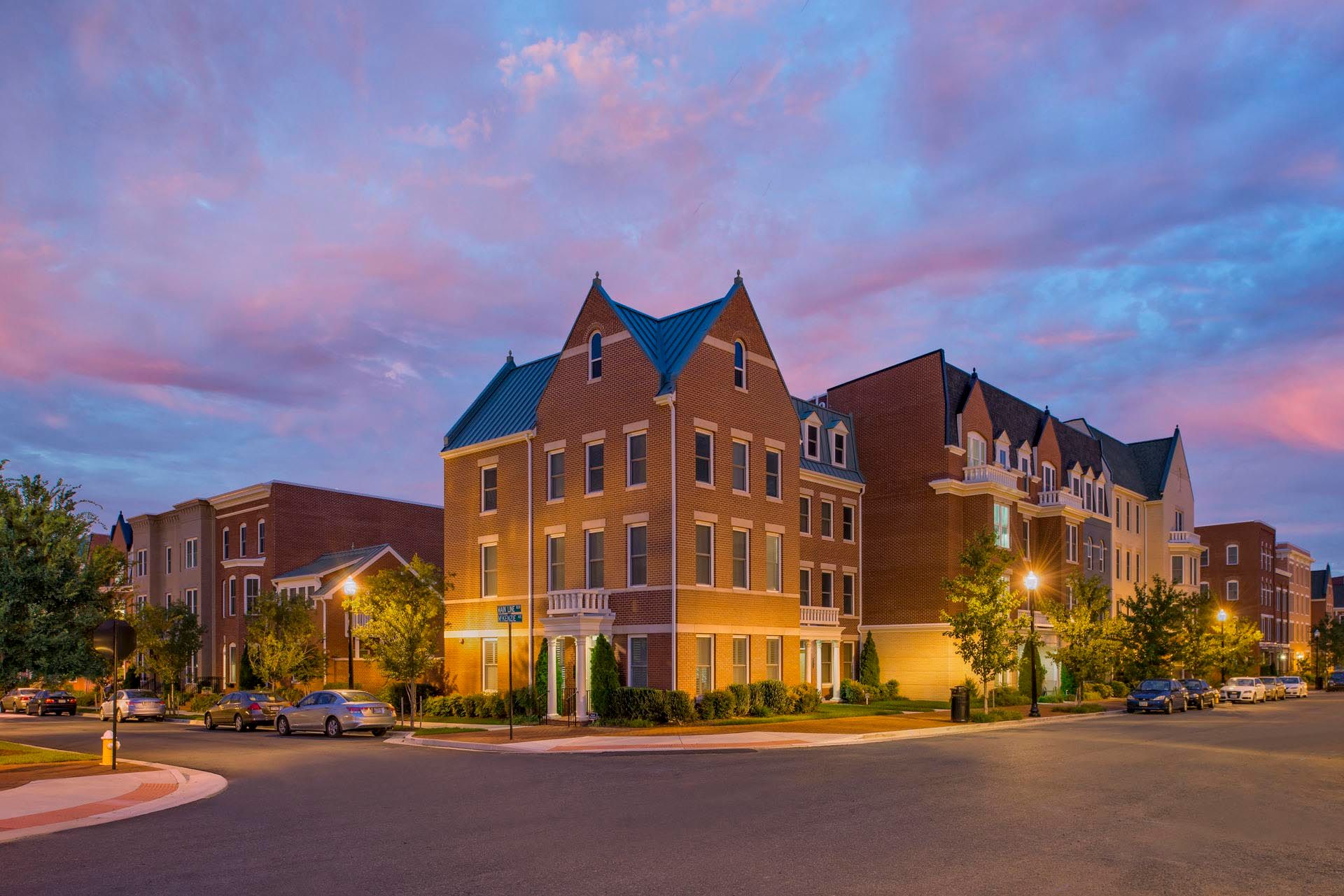A large brick building is sitting on the corner of a street at night.