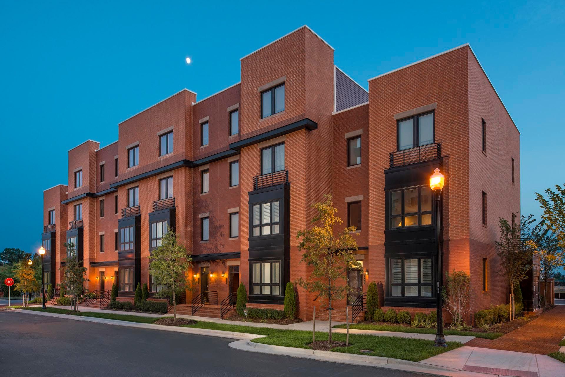 A large brick apartment building with a lot of windows is lit up at night.