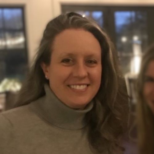 A woman wearing a grey turtleneck smiles for the camera