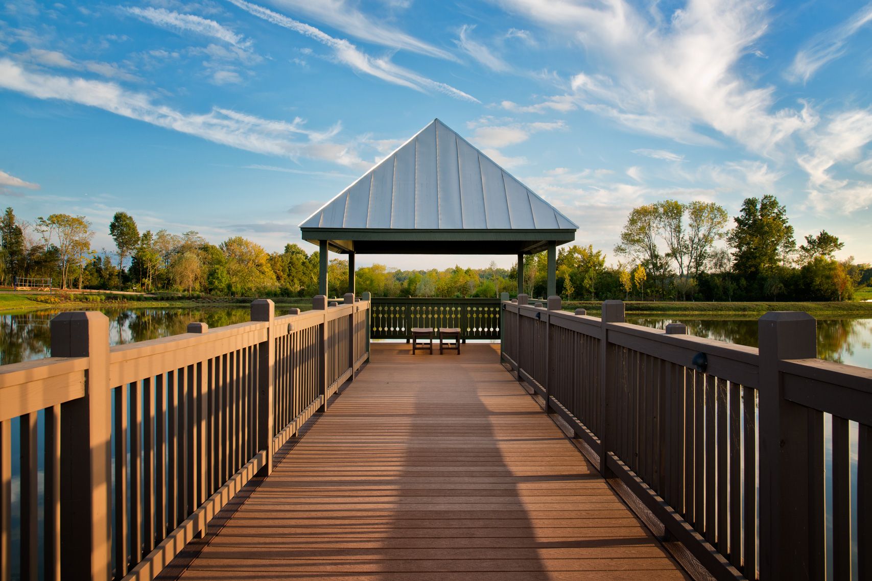 A wooden dock leading to a gazebo overlooking a lake.