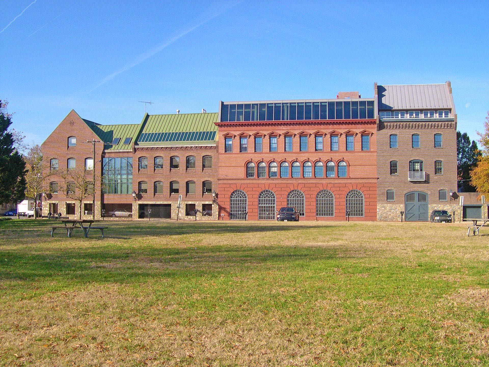 A large brick building with a green roof sits in the middle of a grassy field