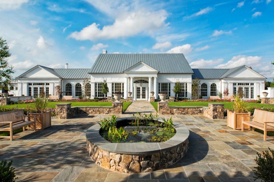 A large white house with a pond in front of it.