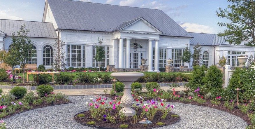 A large white house with a circular garden in front of it.