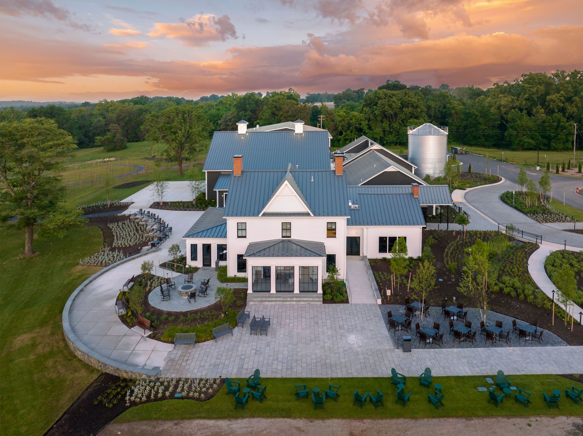 An aerial view of a large white house with a blue roof surrounded by trees.