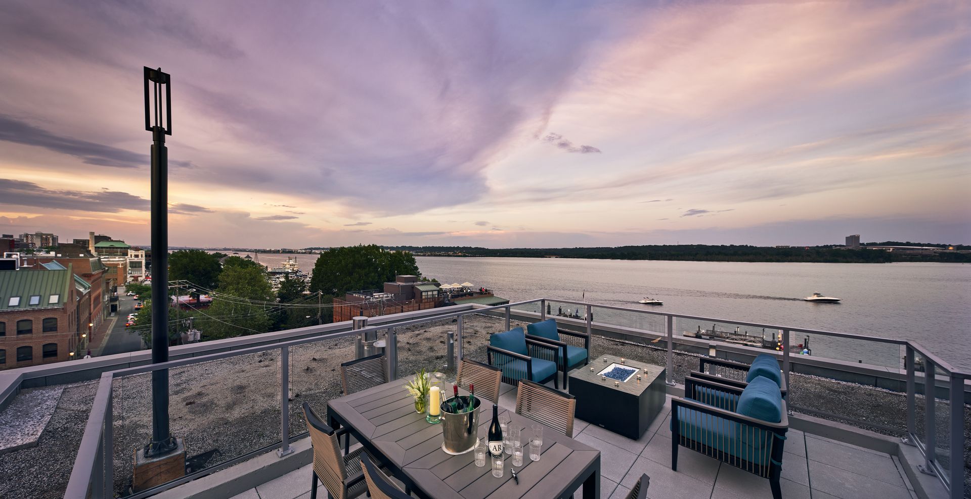 A rooftop deck with a table and chairs overlooking a body of water.