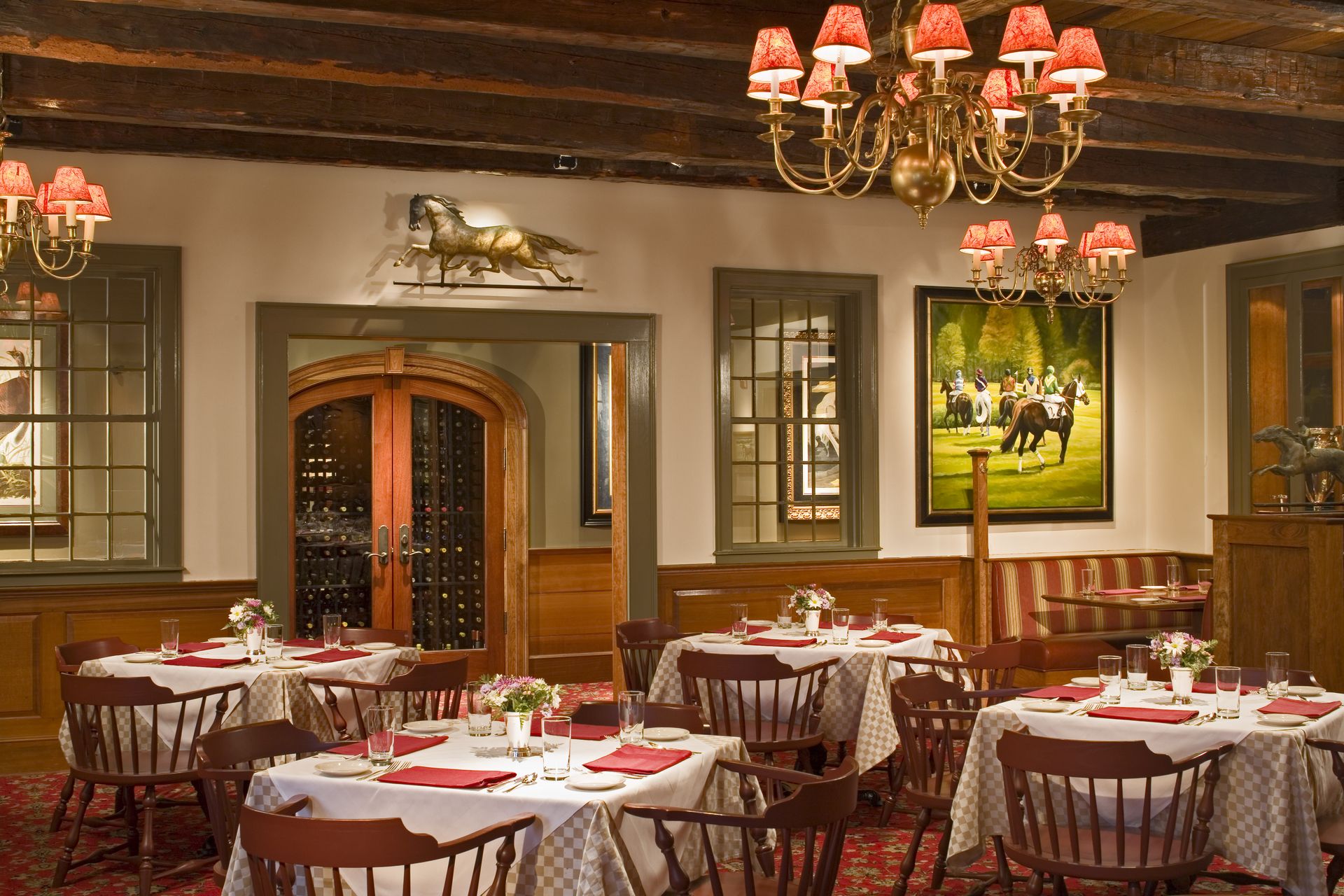 A dining room with tables and chairs and a picture of a horse on the wall