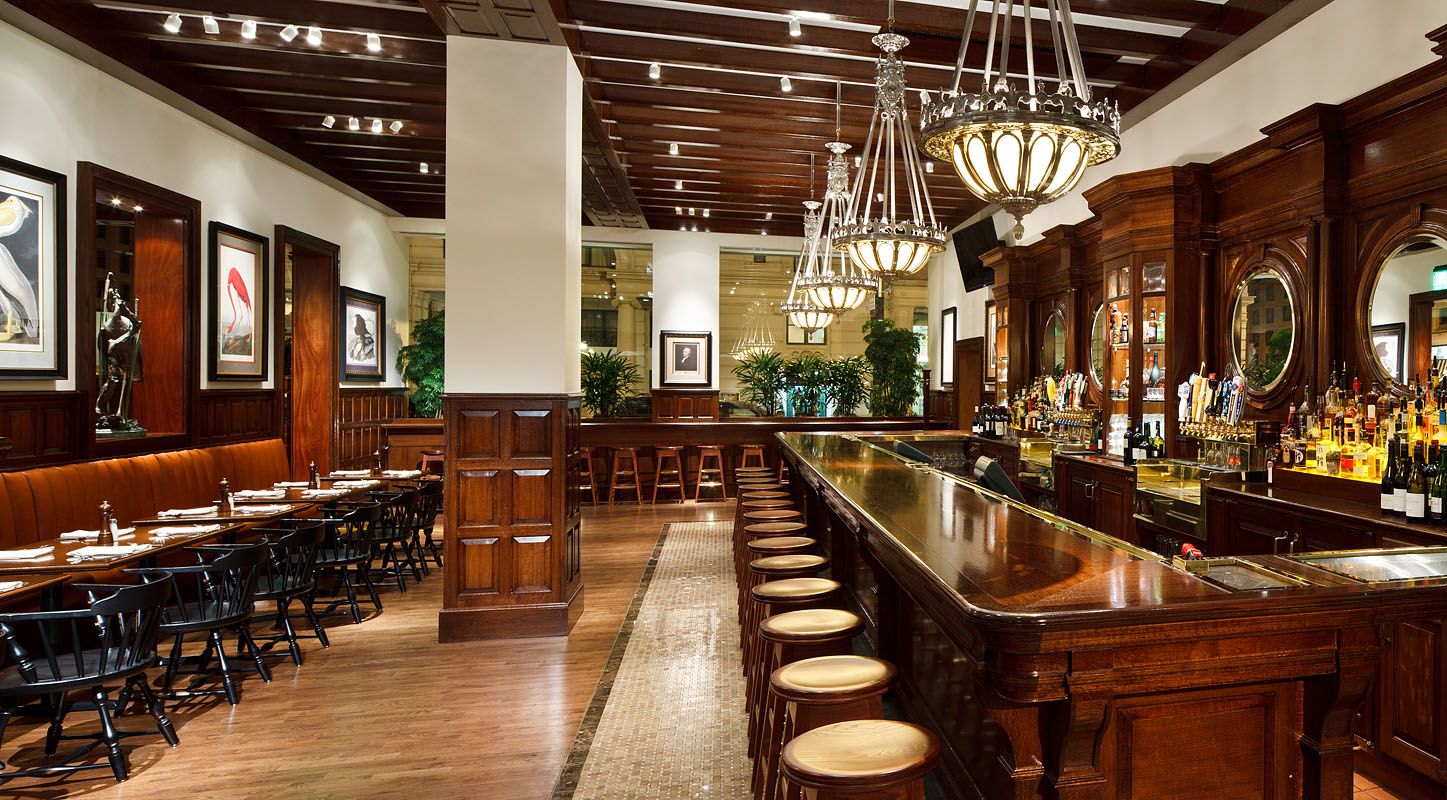 A restaurant with a long bar and tables and chairs