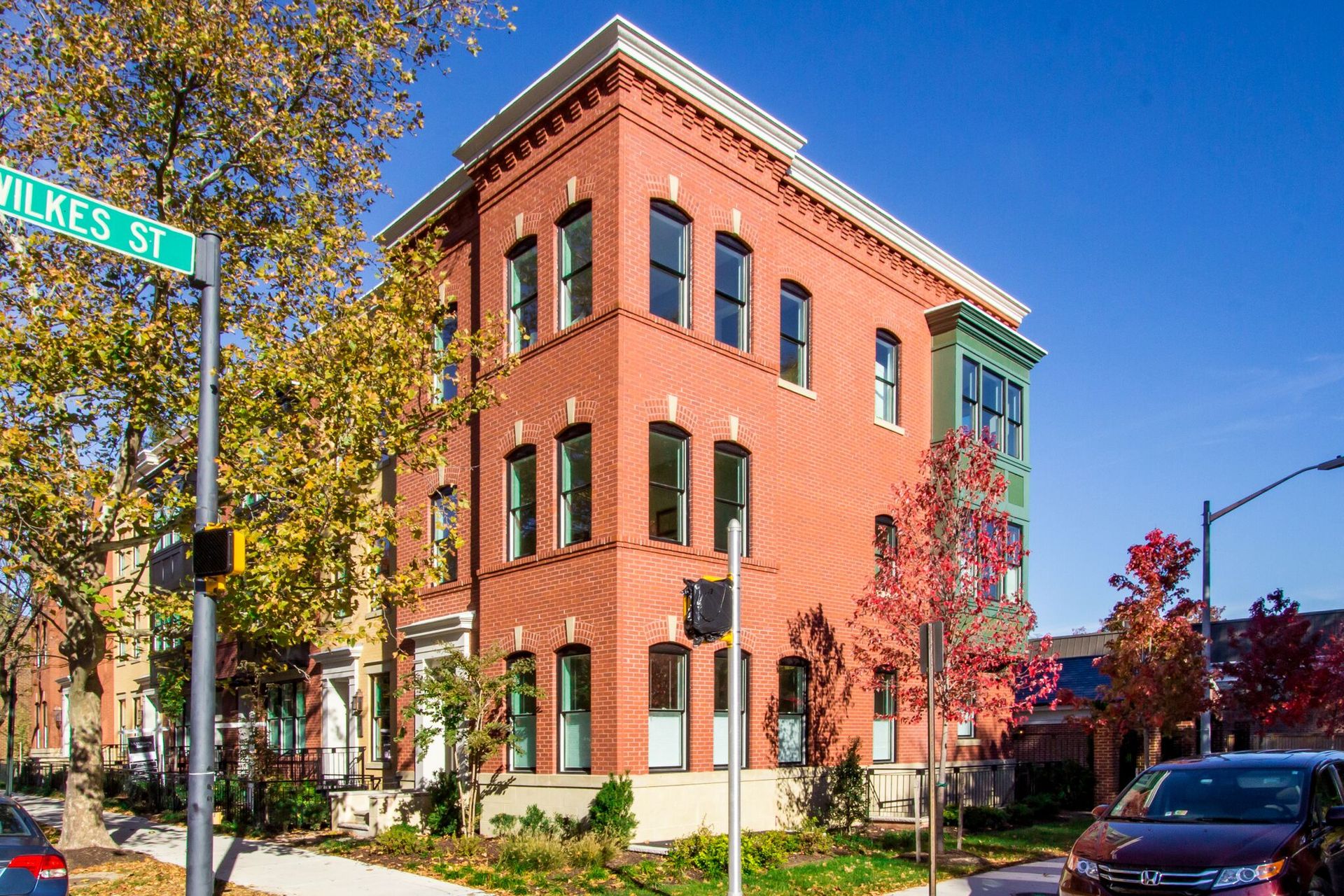 A red brick building with a green street sign on it
